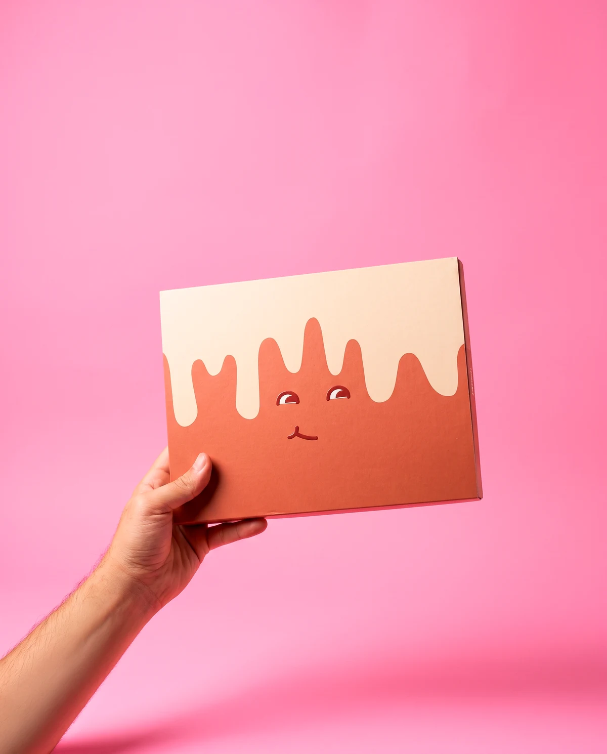 Chocobox cerrada sostenida en la mano sobre fondo rosado